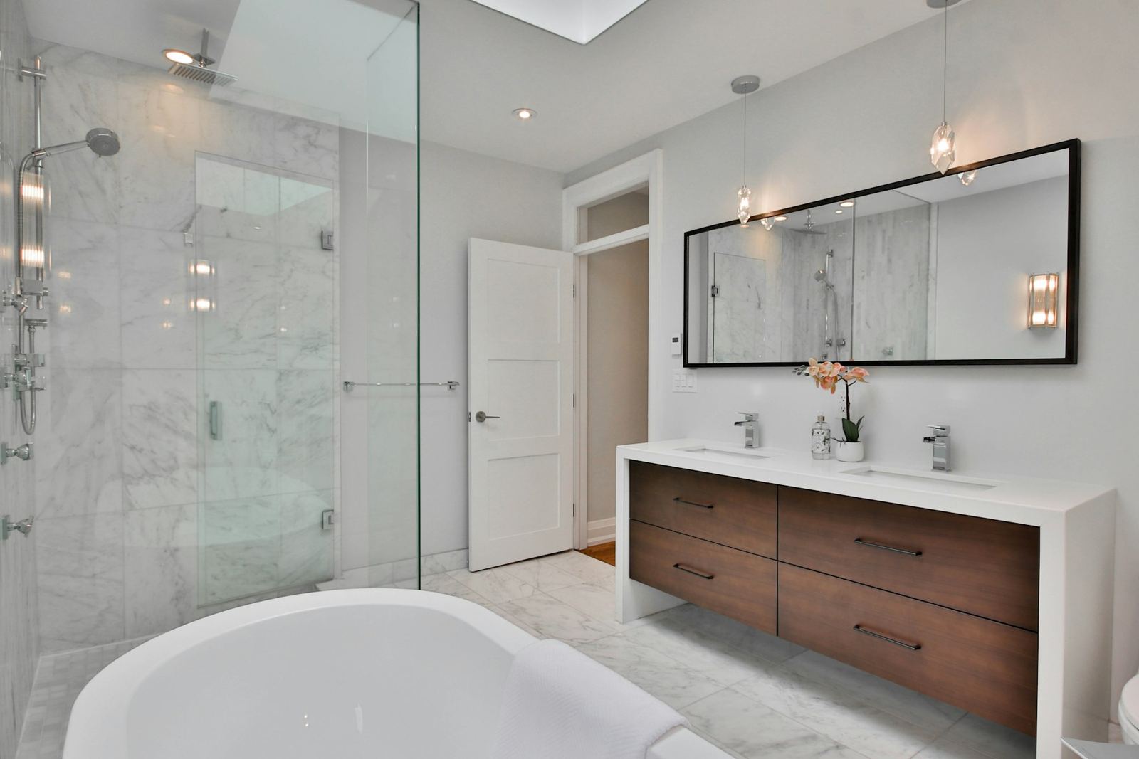 Bathroom with a walnut double vanity, a frameless glass shower and a soaking tub