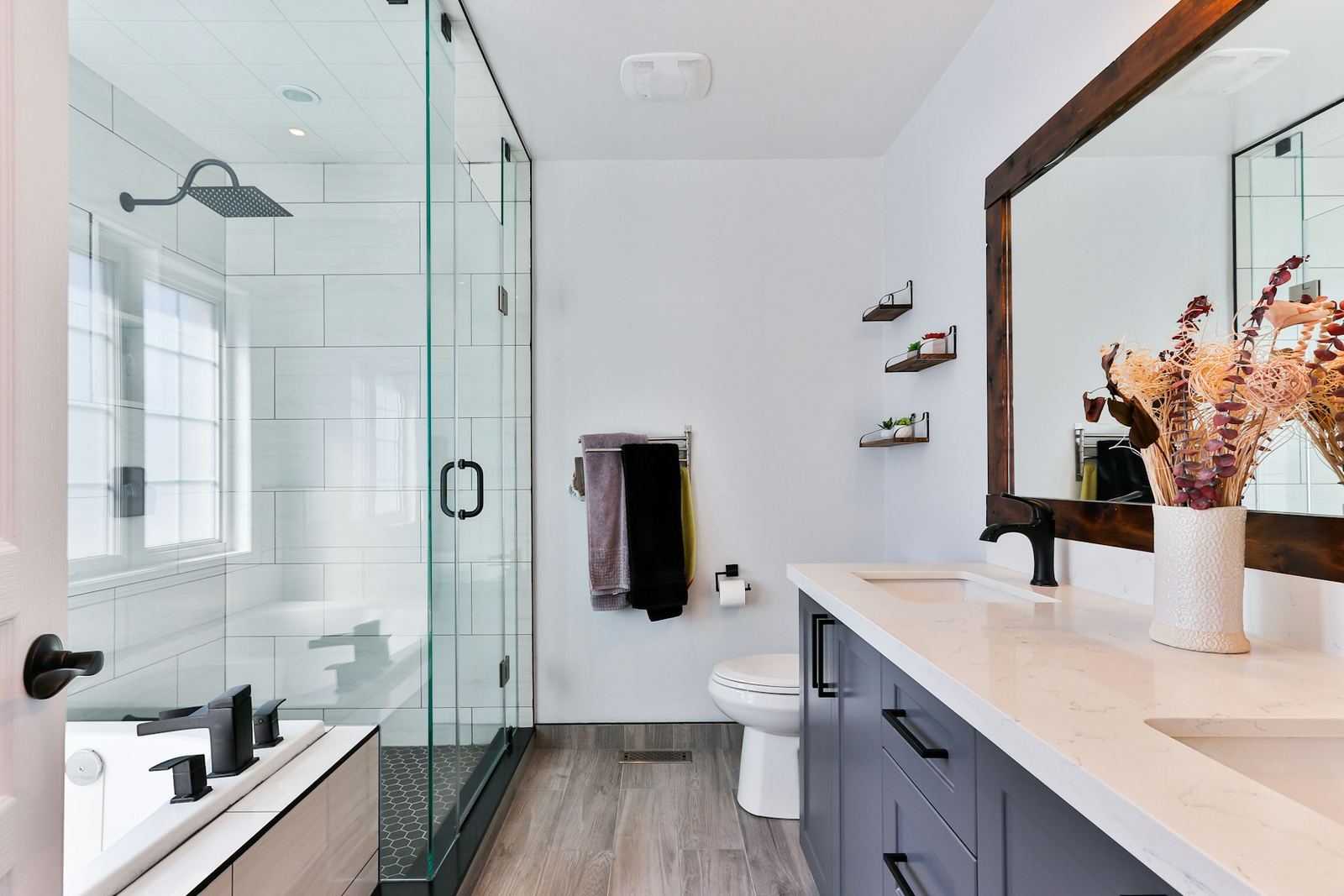 Bathroom with a glass-enclosed shower, a double vanity and a wood-framed mirror
