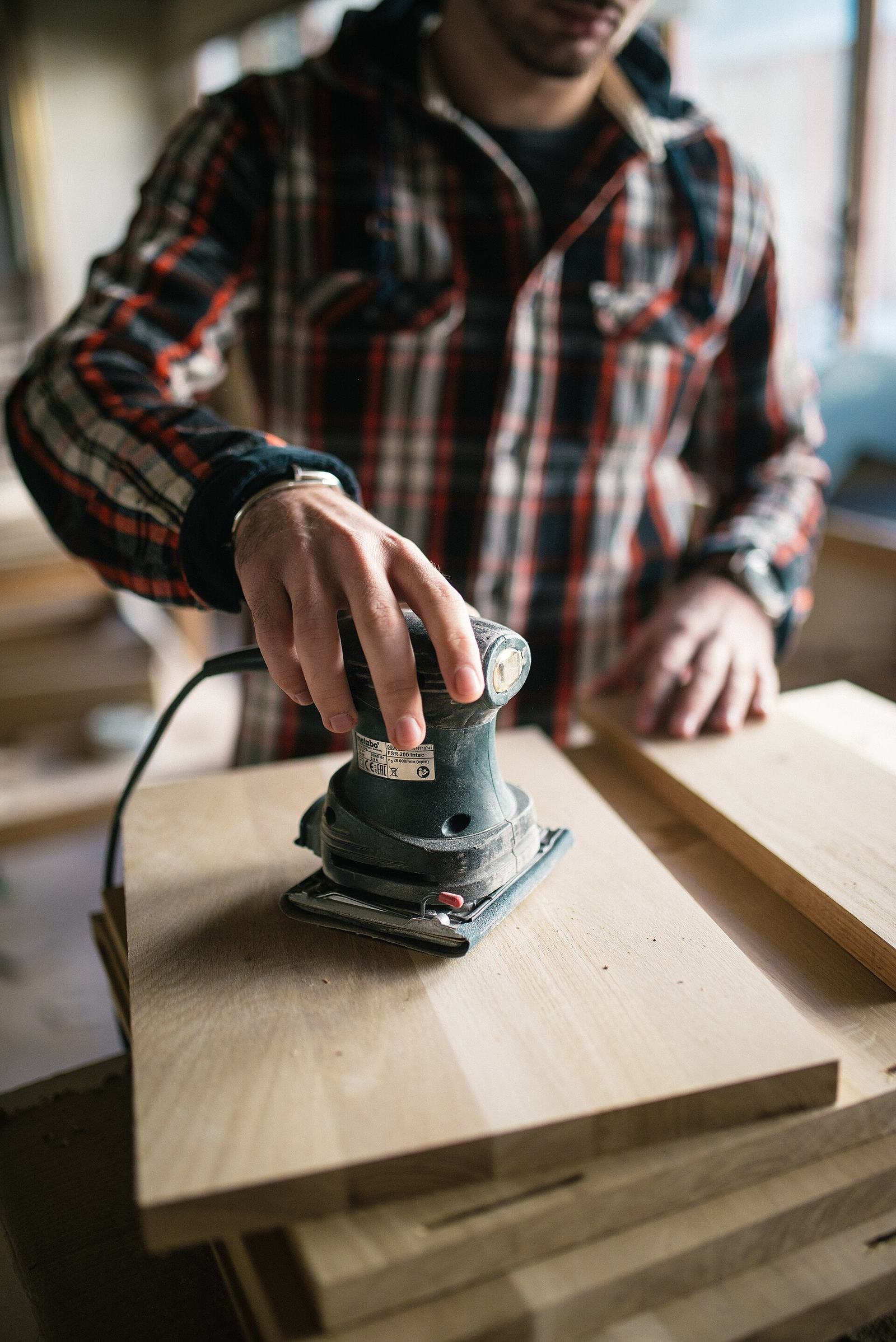 A Harbor Stone carpenter sanding an oak board in the workshop