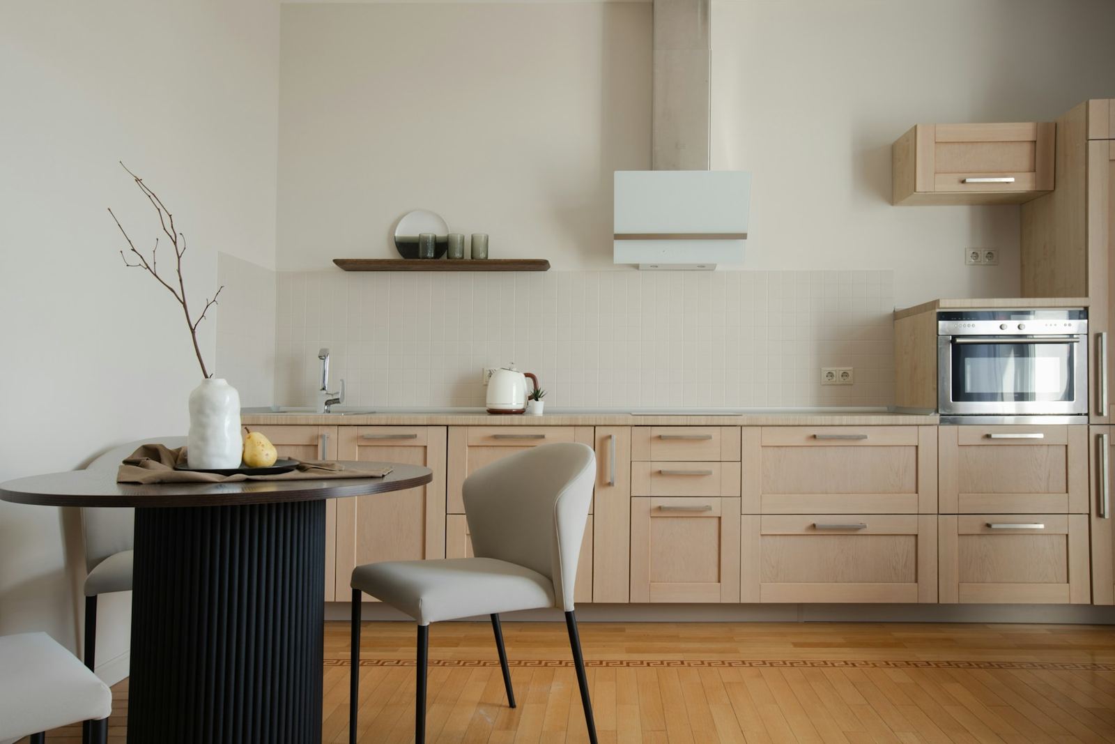 Light-wood kitchen with a round dining table and an oak floor