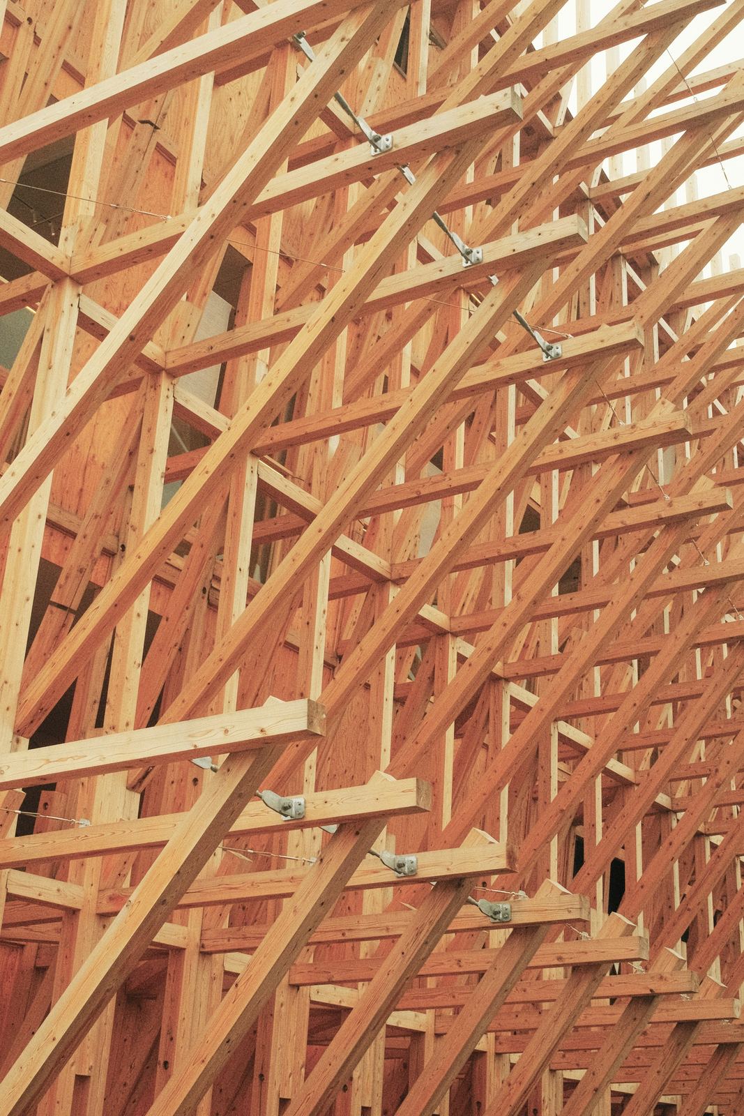 Close-up of pale lumber roof trusses and metal connector plates against a warm background